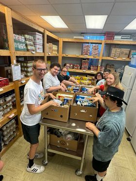 group of people packing boxes of food at a table indoors