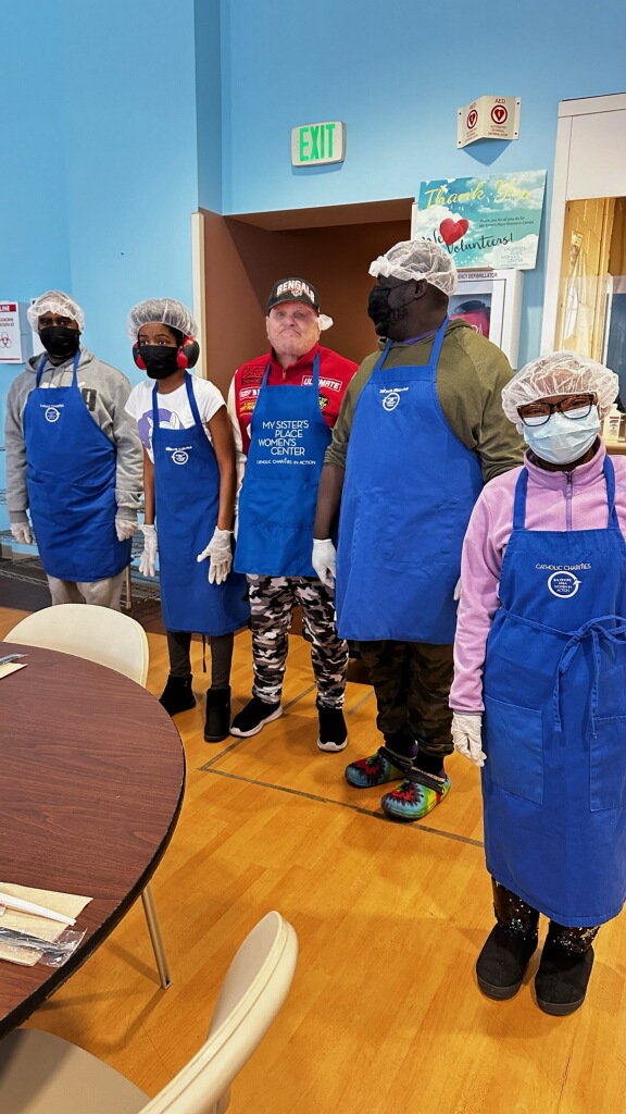 group photo of several people standing in hair nets, blue aprons, and face masks